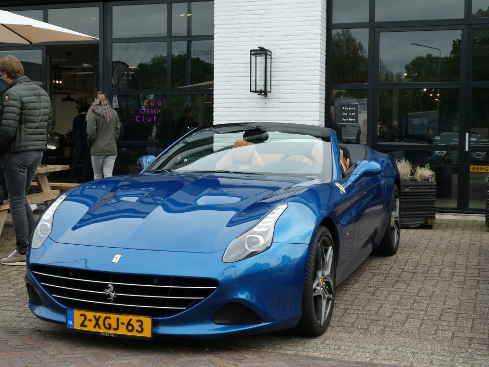 Blauwe Ferrari California staat geparkeerd voor The Octane Club in Naarden, foto carlive.nl